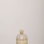 Discover the YAKUSH Candle Snow Queen – a 7" tall soy candle in hand-blown recycled glass, scented with oud, rose, and patchouli, with a 70-hour burn time.